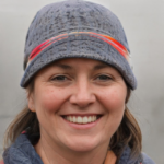 A smiling person wearing a blue hat with red and orange stripes.